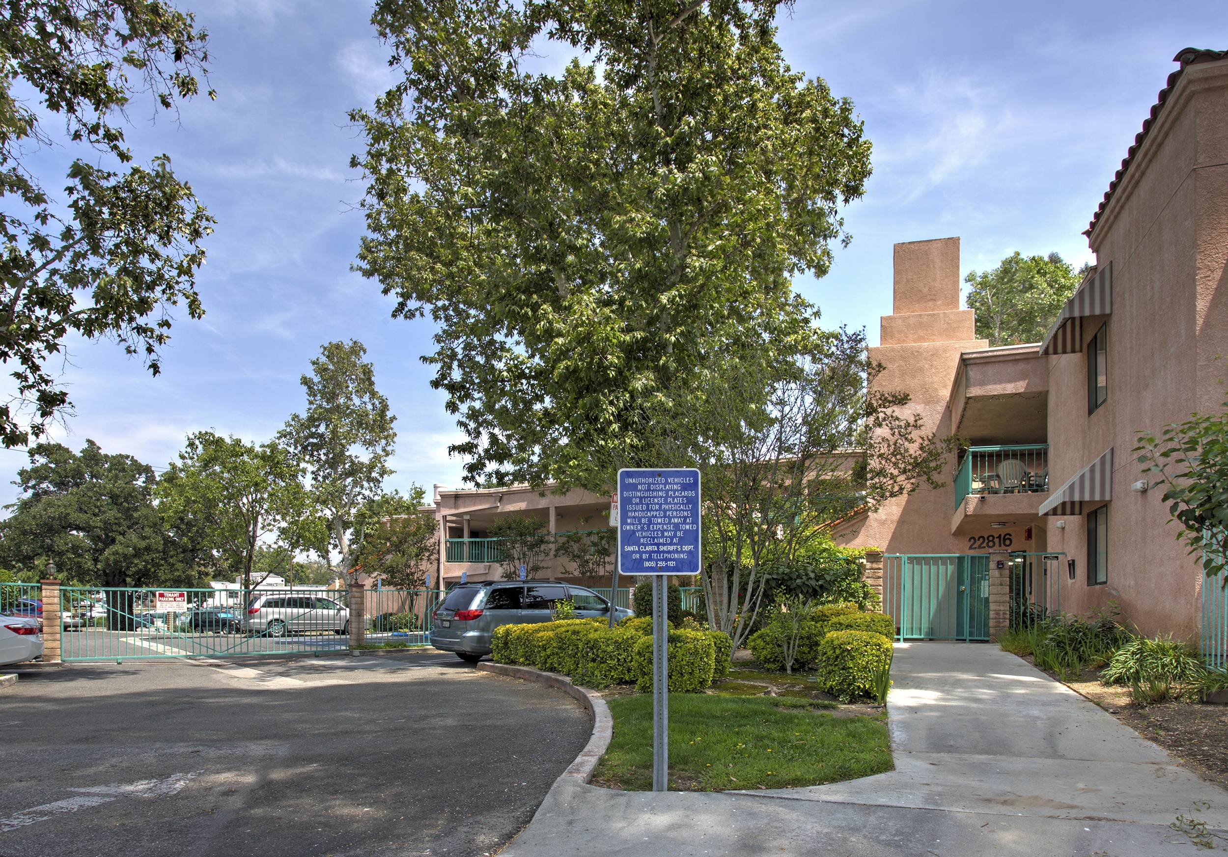 A sign in front of a building with a tree in the foreground.